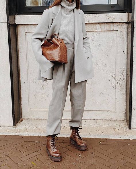 woman wearing grey outfit, leather shoes, and holding a leather bag